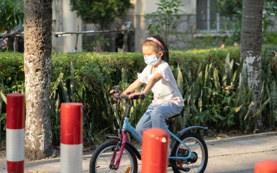 a boy wearing a mask riding a bicycle