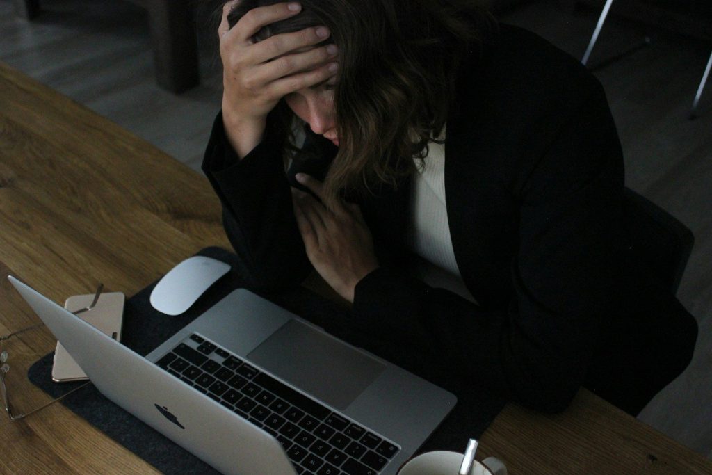 stressed woman with head in hands at laptop